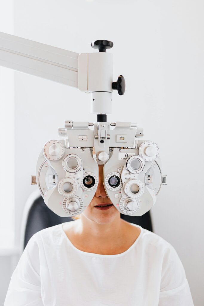 Close-up of a woman undergoing an eye examination using a phoropter in a clinic.